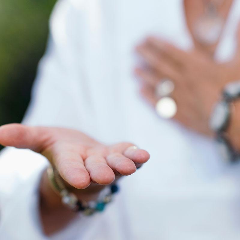 Hand held out in a gesture of healing, with bracelets visible on the wrist.
